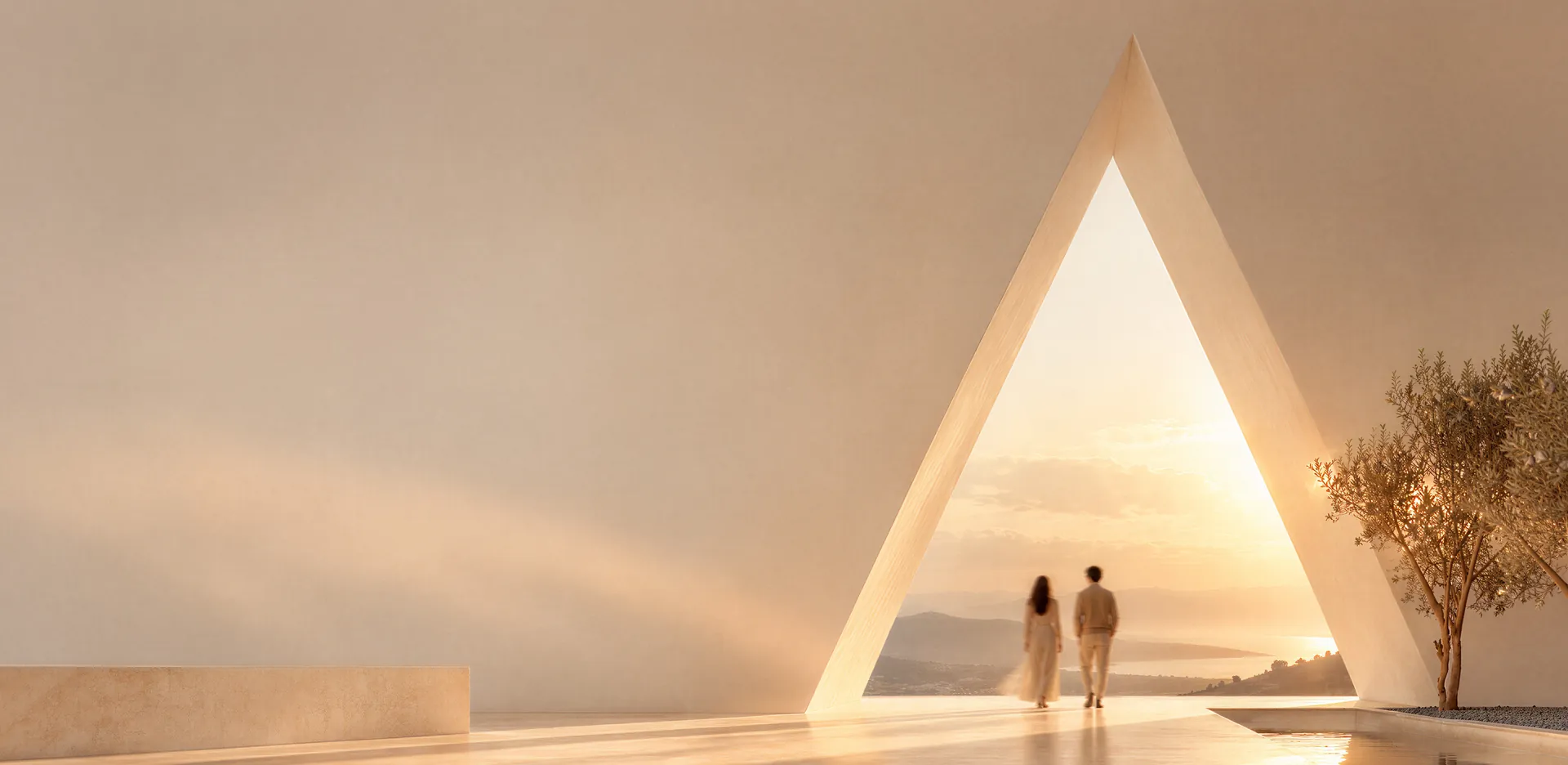 Two people walking through a tall A-shaped arch towards the sea at sunset